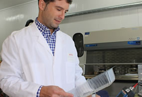 Técnico de AINIA Centro Tecnológico observando un envase tipo bandeja para alimentos; trabajando en un proyecto de innovación en nuevos materiales barrera para envases que alarguen la vida útil de los alimentos