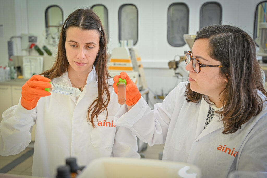 Dos investigadoras de AINIA observan muestras en tubos de laboratorio.
